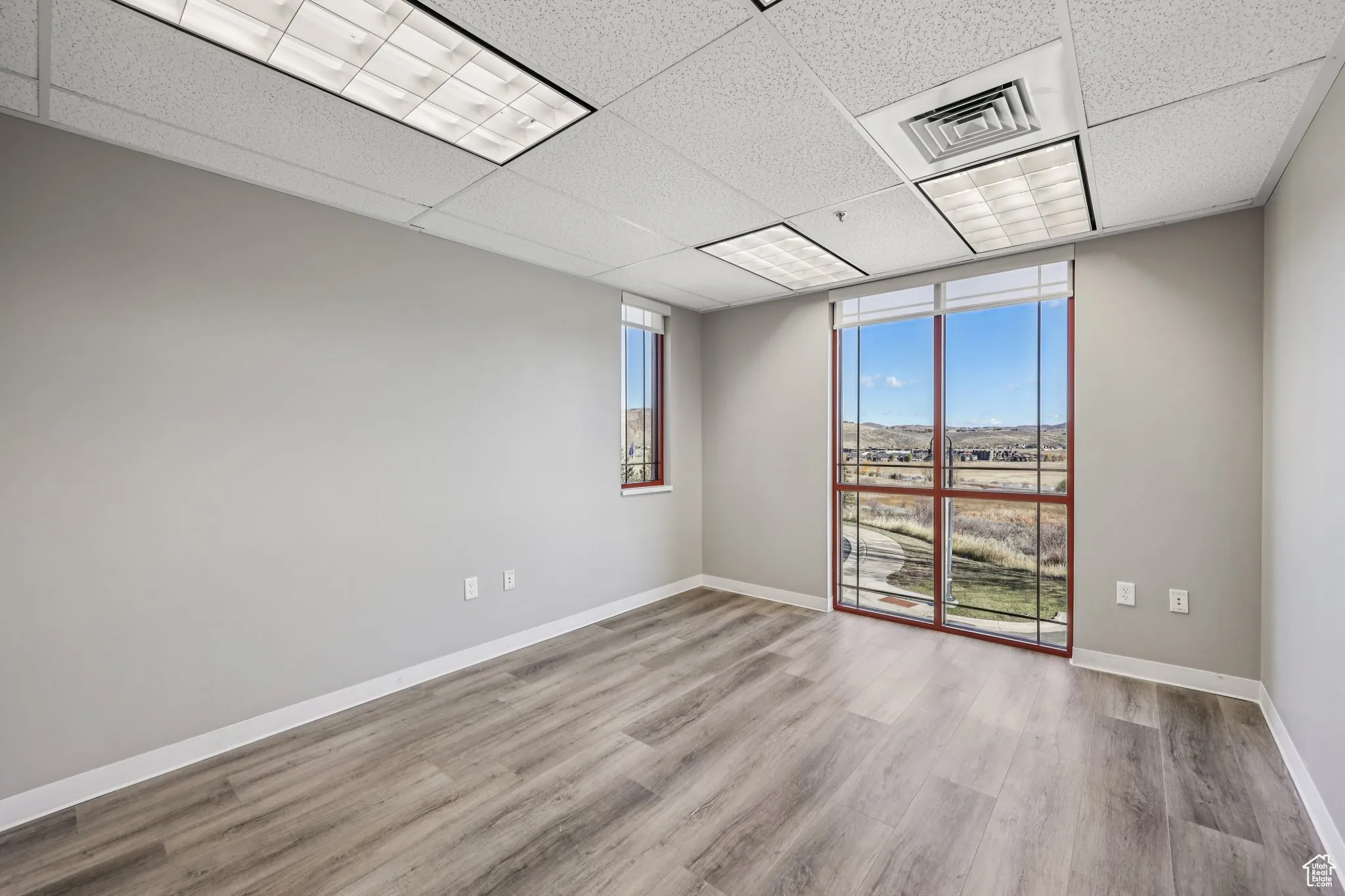 Empty room featuring a drop ceiling and light wood-style floors
