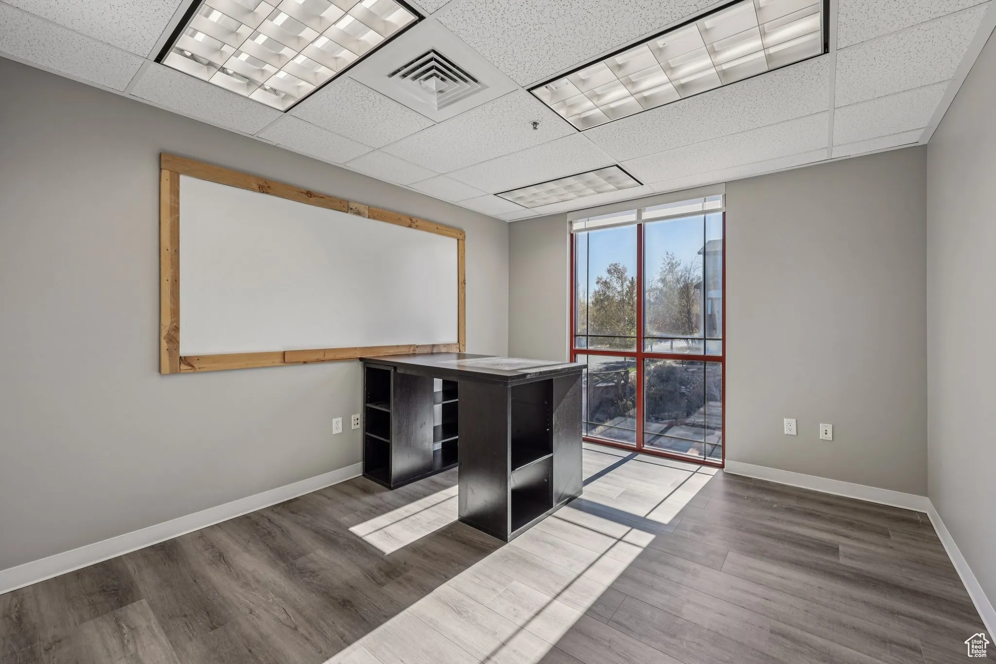 Unfurnished office with a paneled ceiling and wood finished floors