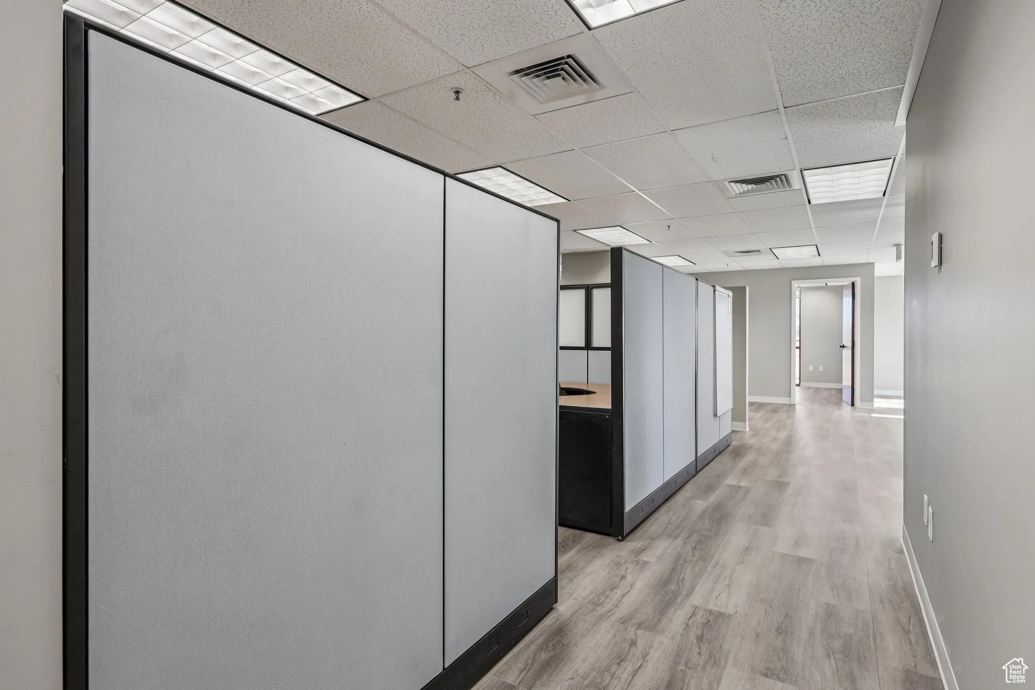 Hallway featuring a paneled ceiling and light wood-style floors