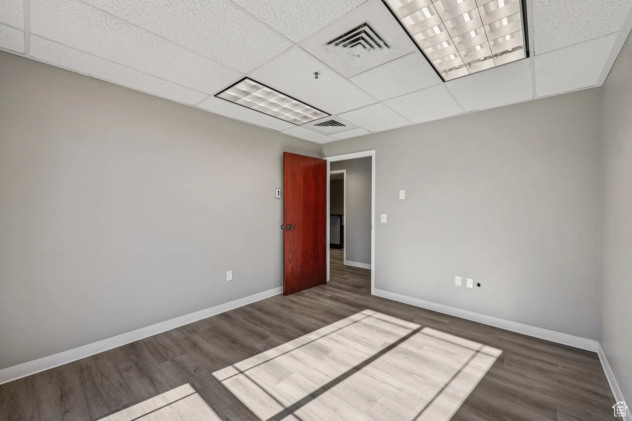 Spare room with dark wood-style floors and a drop ceiling