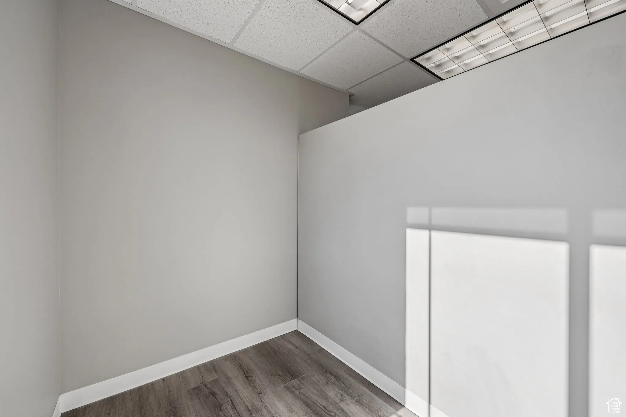 Empty room with a paneled ceiling and wood finished floors