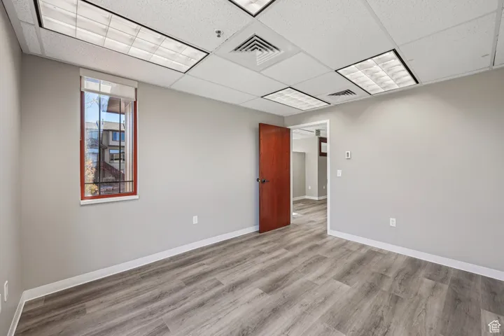 Unfurnished room featuring wood finished floors and a drop ceiling