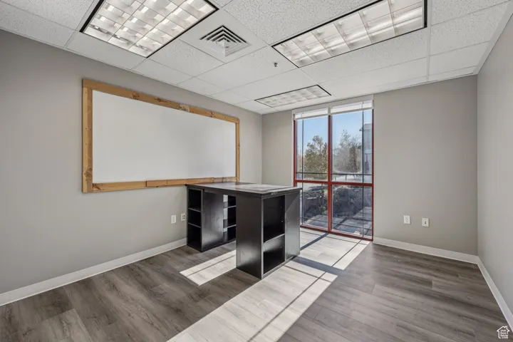 Unfurnished office with a paneled ceiling and wood finished floors