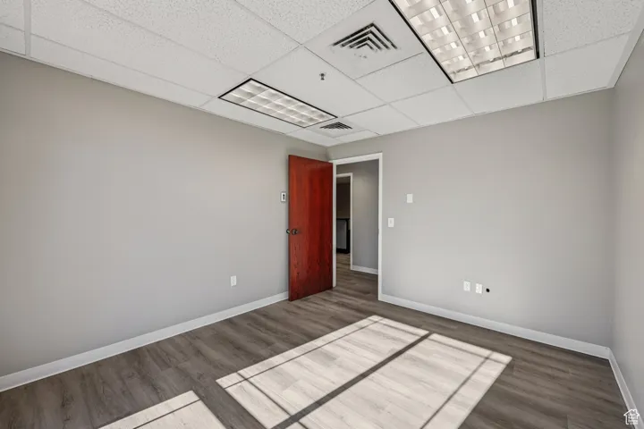 Spare room with dark wood-style floors and a drop ceiling
