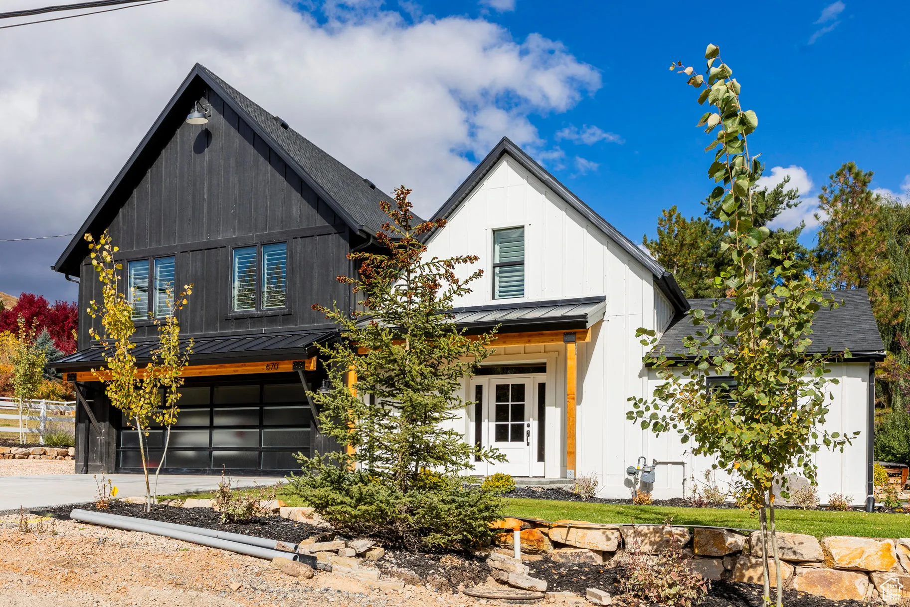 Modern inspired farmhouse featuring a standing seam roof, a metal roof, a garage, board and batten siding, and driveway