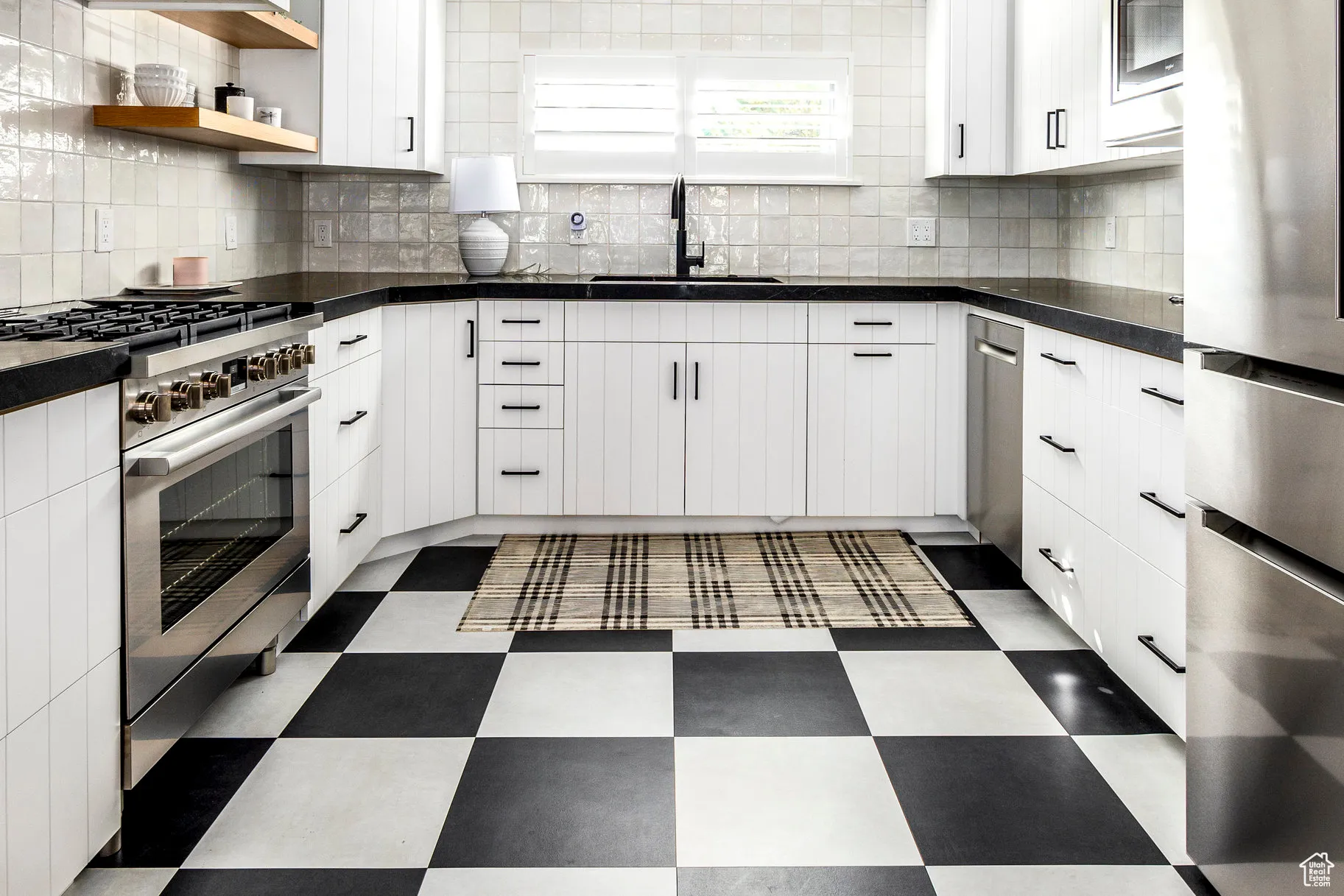 Kitchen with appliances with stainless steel finishes, white cabinetry, tasteful backsplash, dark floors, and open shelves