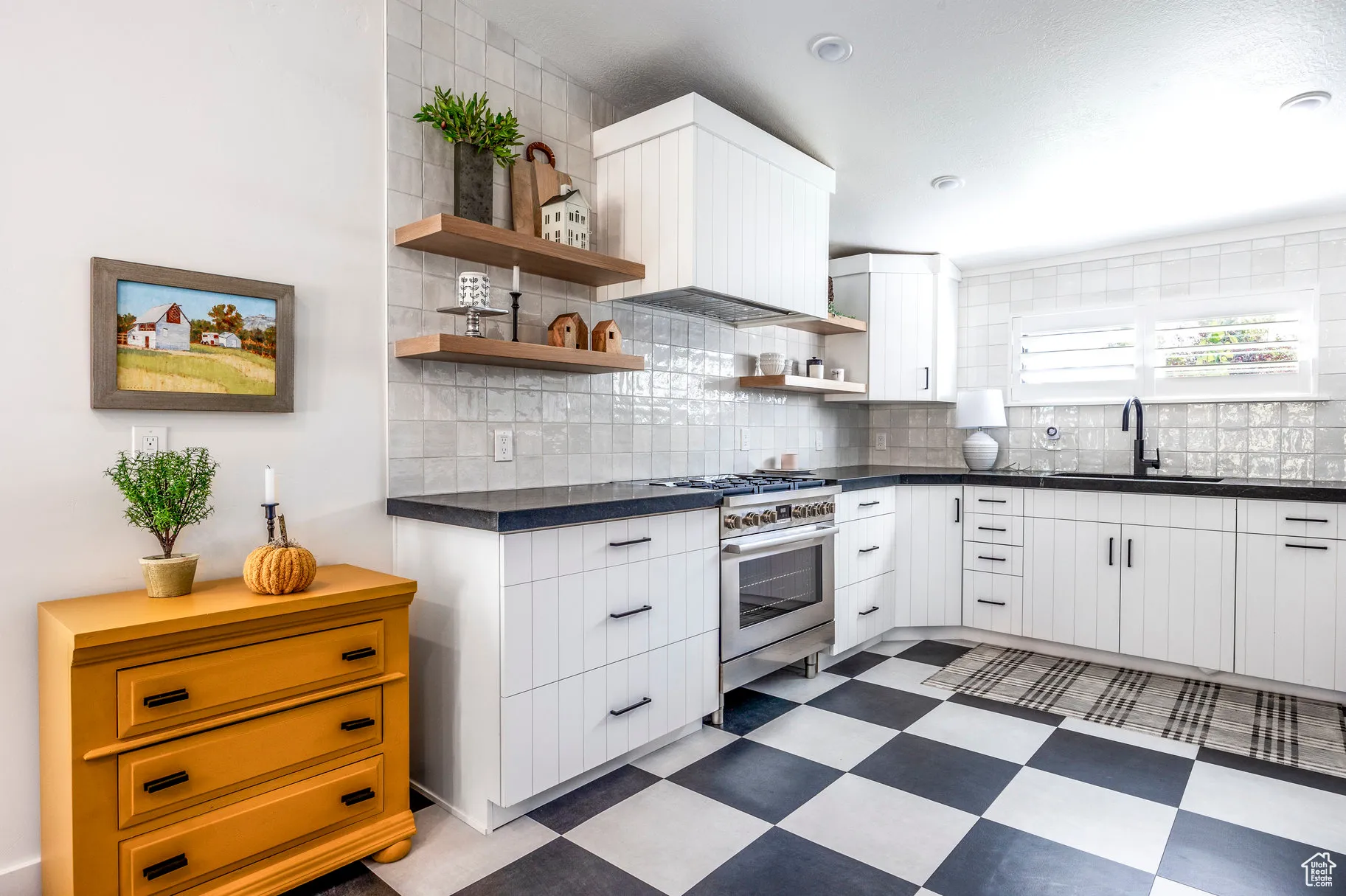 Kitchen with dark countertops, white cabinetry, dark flooring, and gas range