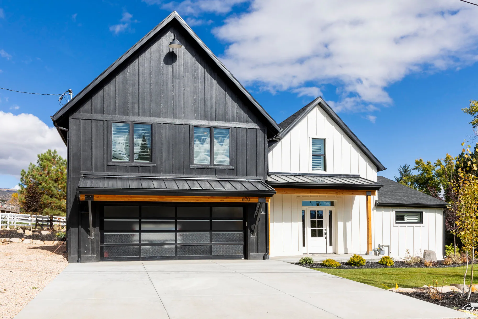 Modern farmhouse style home with a garage, a standing seam roof, a metal roof, concrete driveway, and covered porch