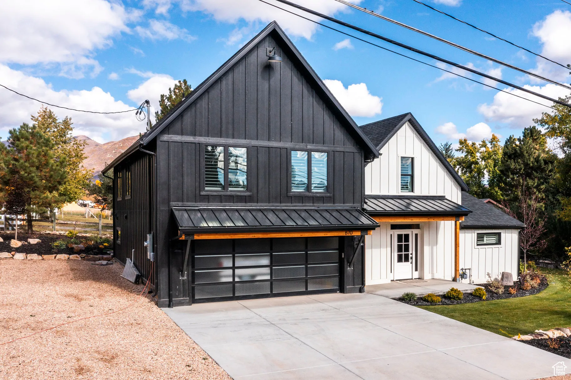 Modern inspired farmhouse featuring a standing seam roof, board and batten siding, a garage, a metal roof, and driveway