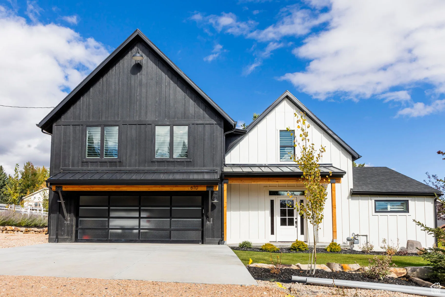 Modern inspired farmhouse featuring a garage, driveway, a metal roof, a standing seam roof, and covered porch