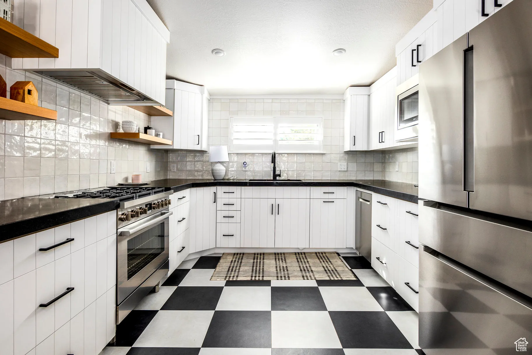 Kitchen featuring stainless steel appliances, dark floors, open shelves, white cabinets, and decorative backsplash