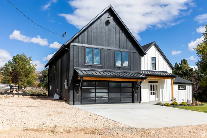Modern farmhouse style home with a standing seam roof, concrete driveway, a garage, a metal roof, and board and batten siding
