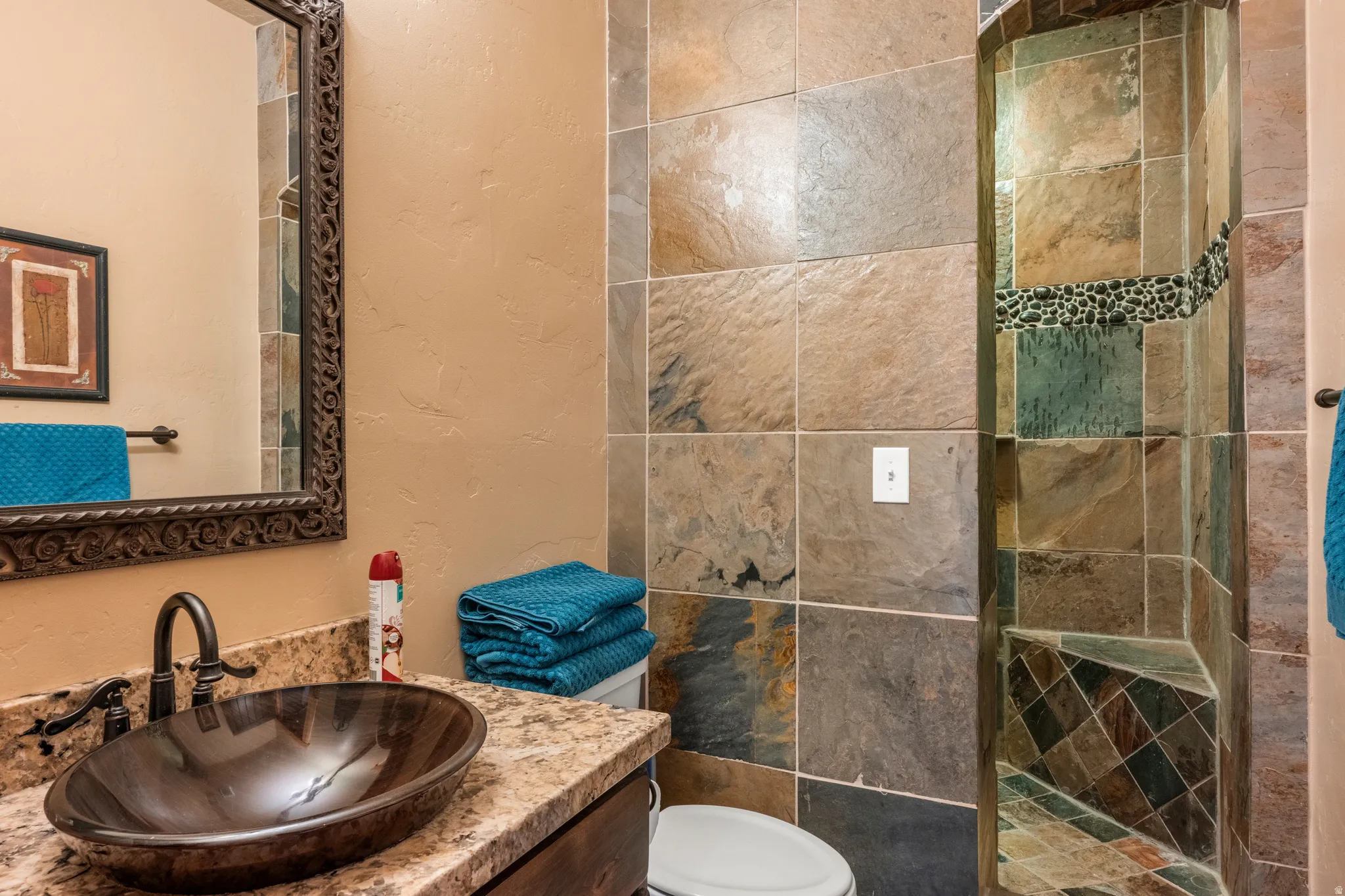 Full bath with a textured wall, vanity, and a walk in shower