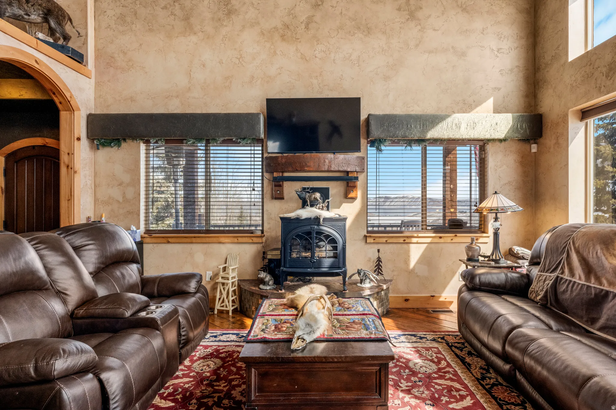 Living area featuring a wood stove, hardwood / wood-style floors, arched walkways, and a high ceiling