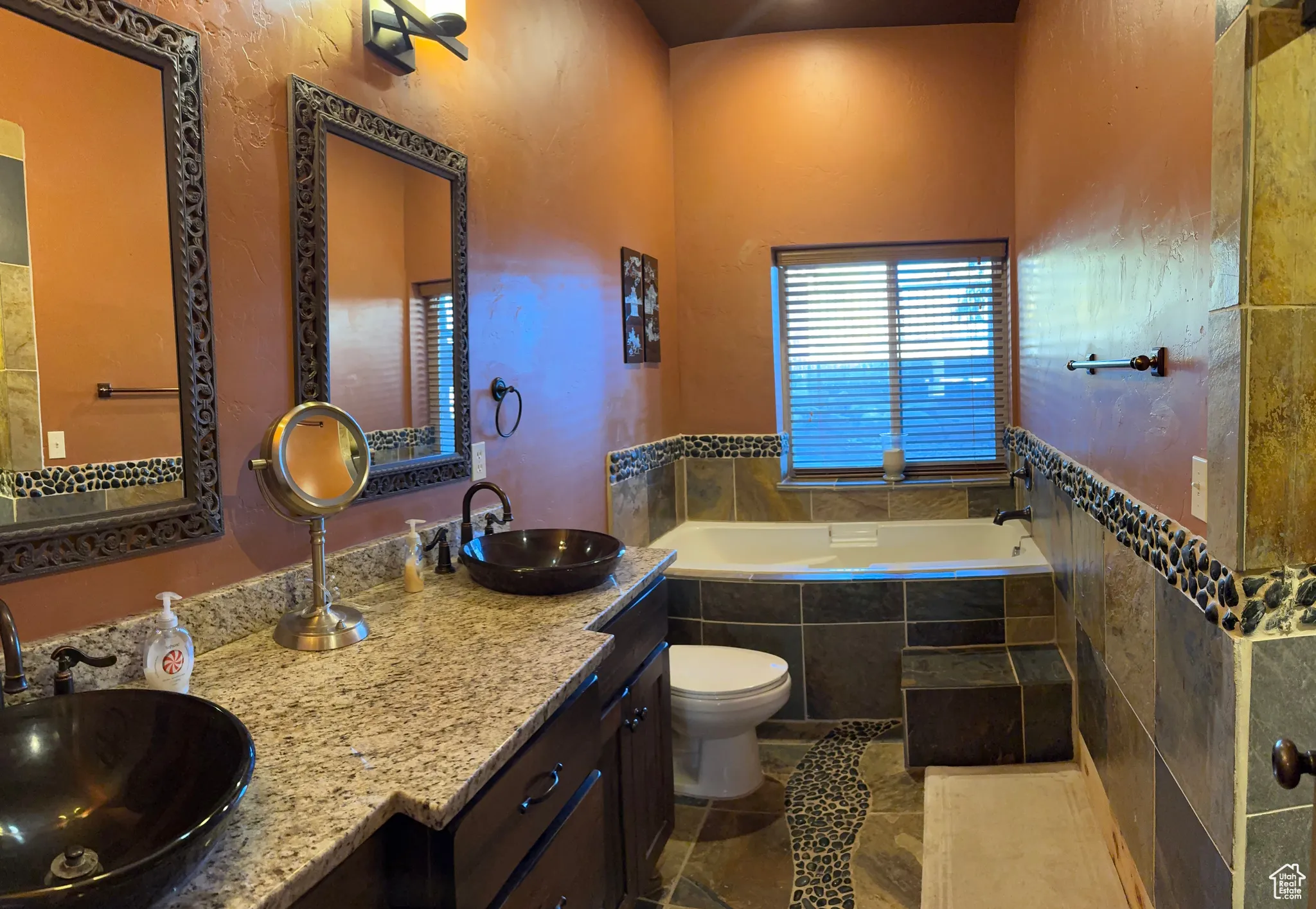 Full bathroom featuring double vanity, a garden tub, and a textured wall