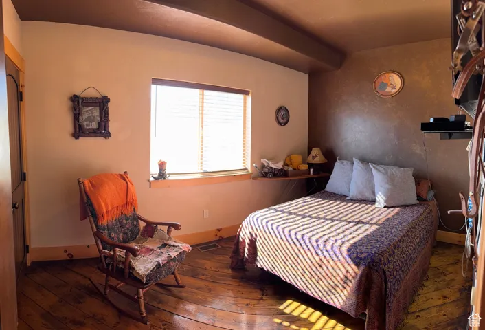 Bedroom featuring dark wood-style flooring and beam ceiling