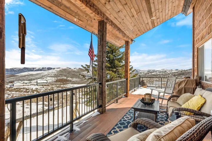 Snow covered back of property featuring an outdoor living space, a mountain view, and a patio area