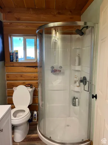 Full bathroom featuring vanity, a stall shower, wood finished floors, wood ceiling, and log walls
