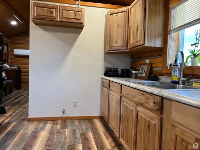 Kitchen featuring light wood finished floors, light countertops, brown cabinetry, and vaulted ceiling
