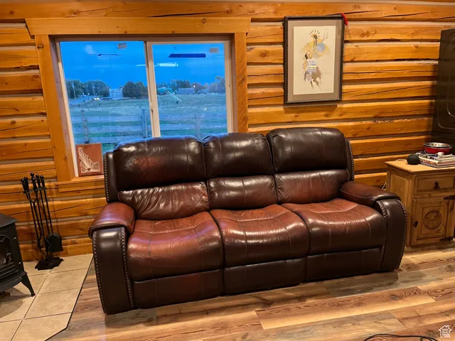 Living area featuring rustic walls, a wood stove, and wood finished floors
