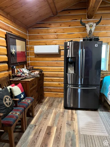 Kitchen with refrigerator with ice dispenser, light wood finished floors, wood ceiling, and wood walls