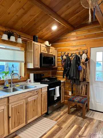 Kitchen featuring range with gas stovetop, light wood-type flooring, light countertops, wooden ceiling, and stainless steel microwave