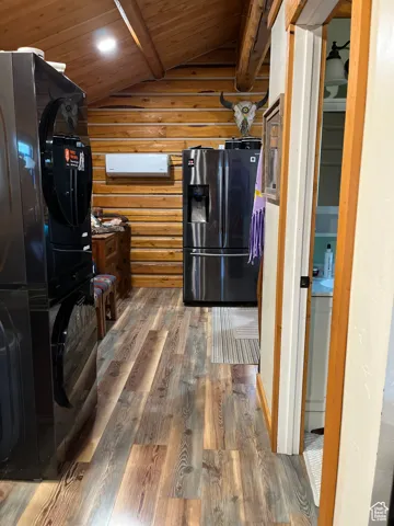 Kitchen featuring wood finished floors, fridge with ice dispenser, wooden ceiling, black refrigerator, and log walls