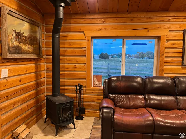 Tiled living area featuring a wood stove, log walls, and wooden ceiling