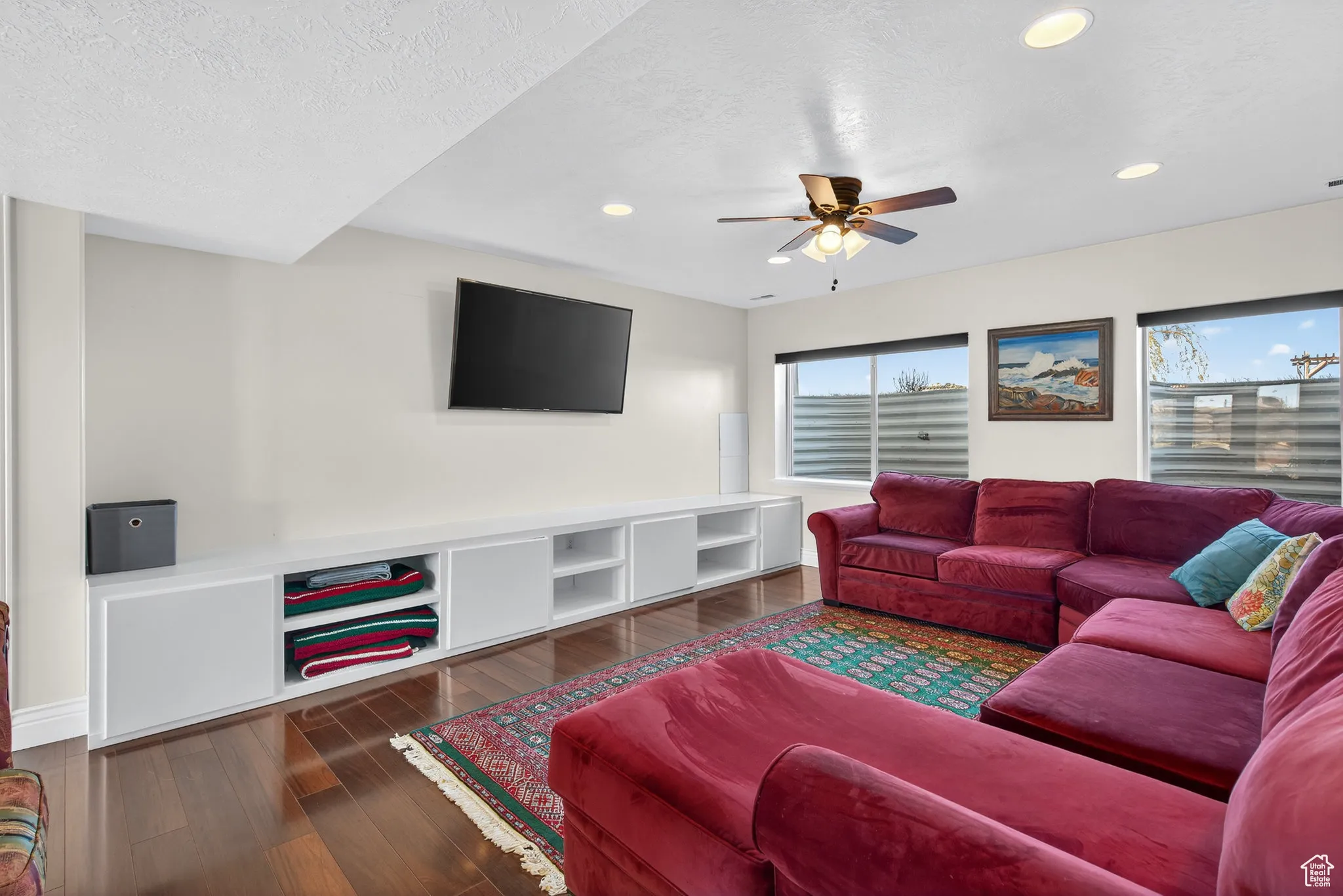 Basement living room featuring a ceiling fan, wood-style flooring and recessed lighting.