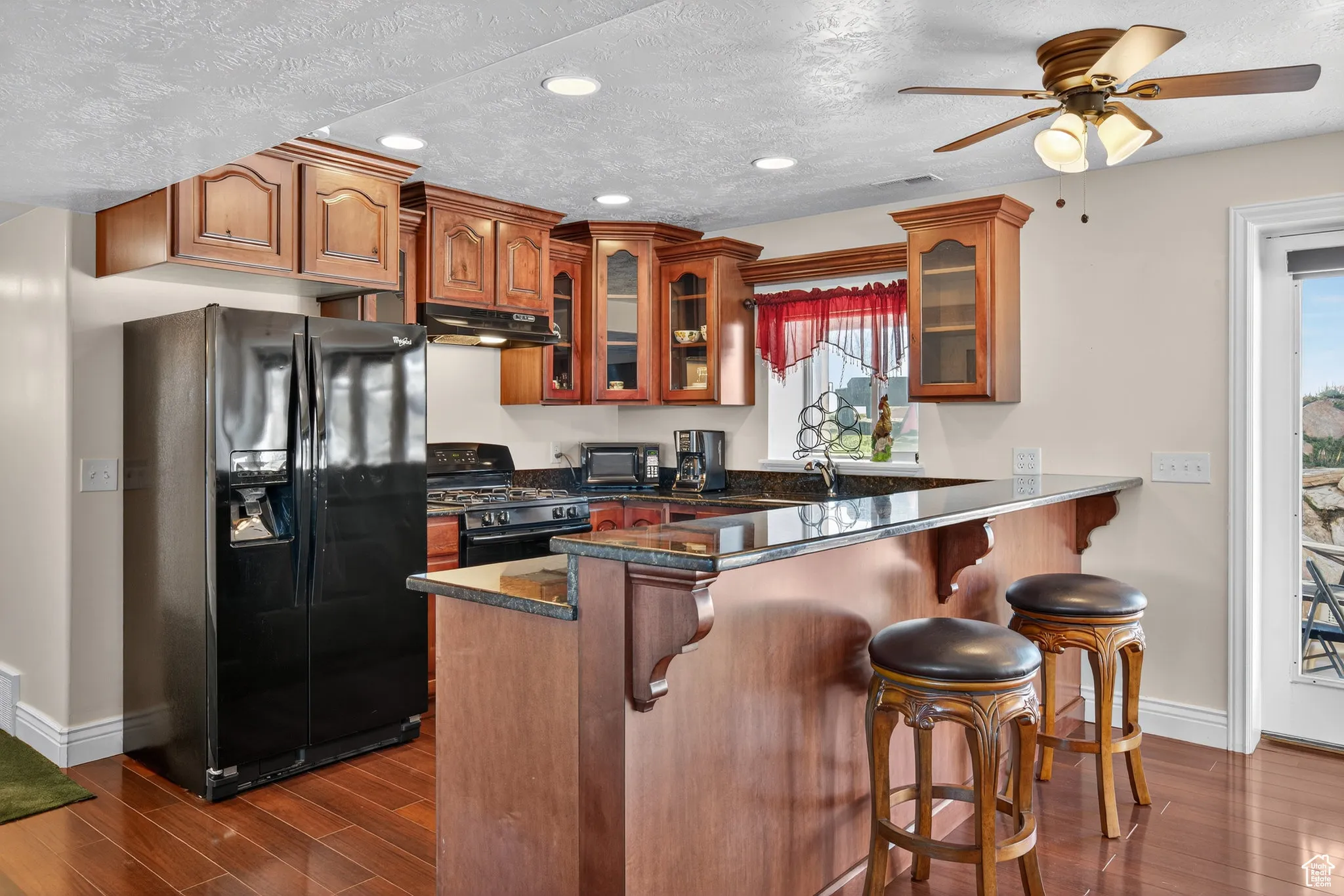 Kitchen featuring black appliances, cabinets,  wood style floors and a bar.
