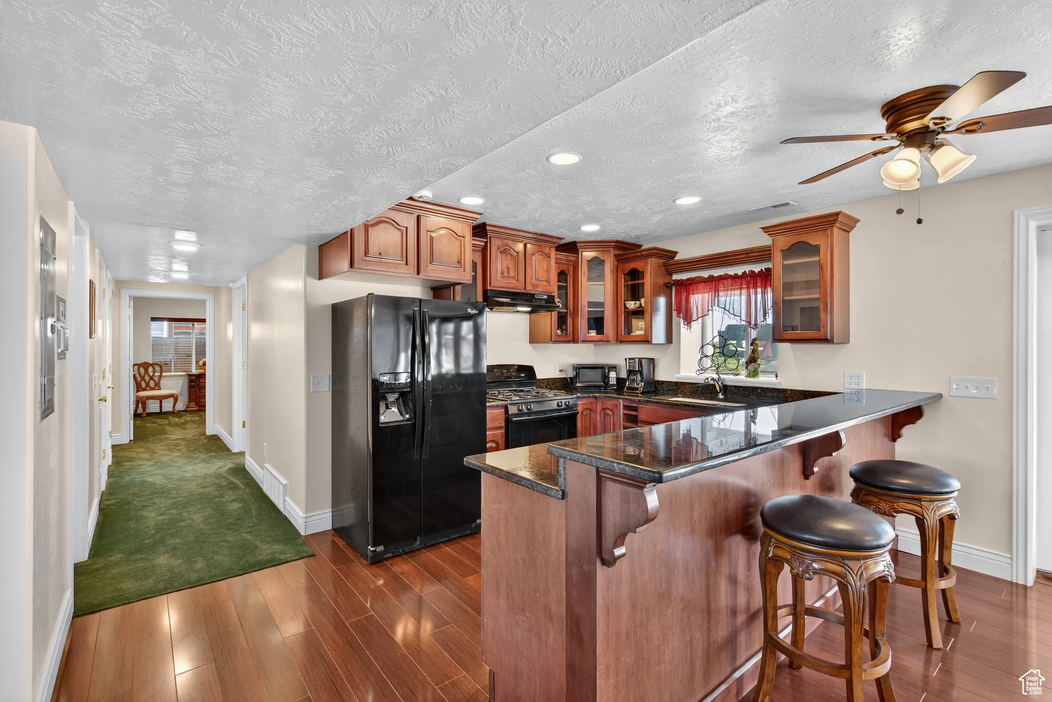 Basement kitchen with black appliances, dark wood-type flooring, recessed lighting, cabinets, and ceiling fan.