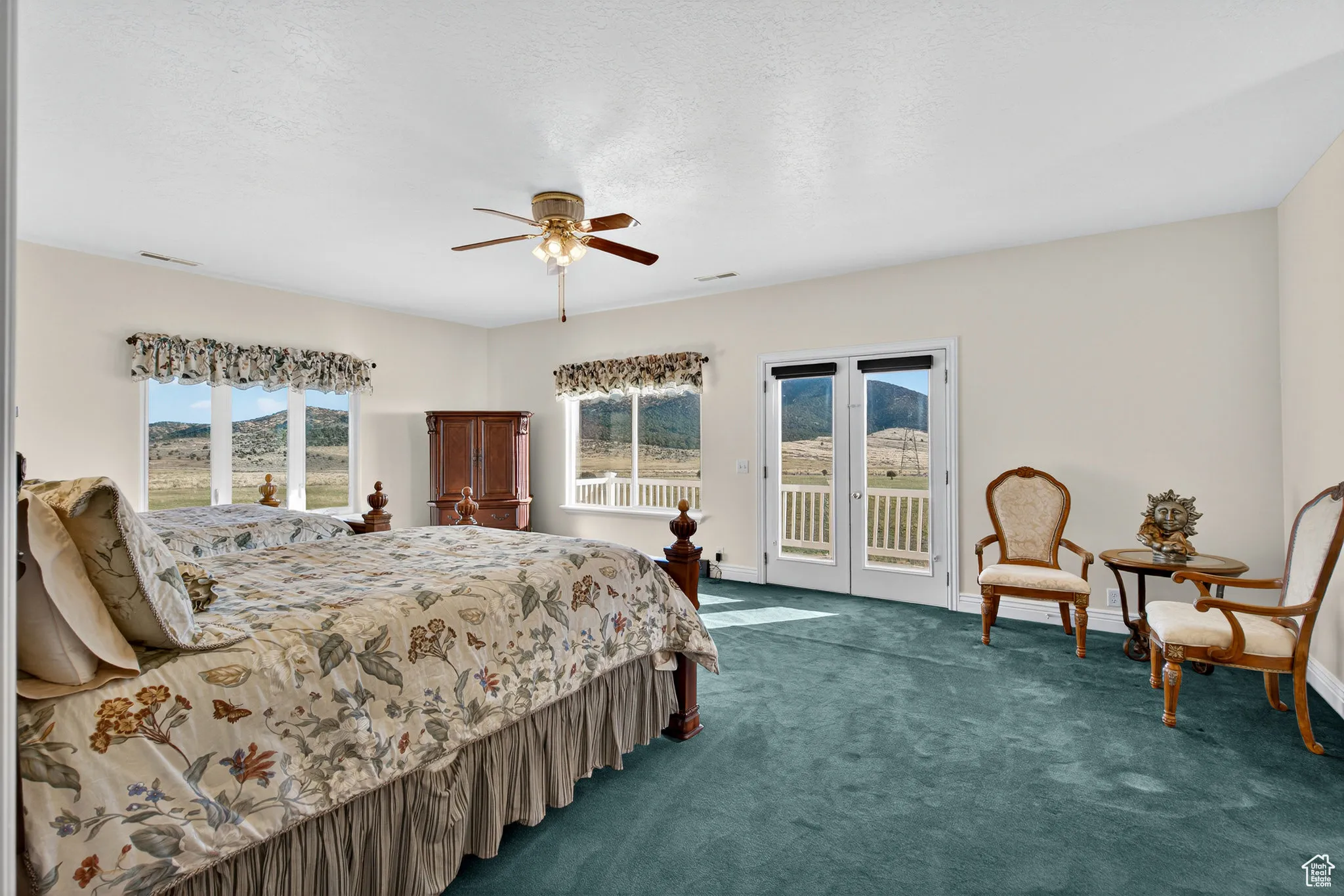 Large bedroom featuring multiple windows, carpet, ceiling fan, and access to East side second floor balcony.