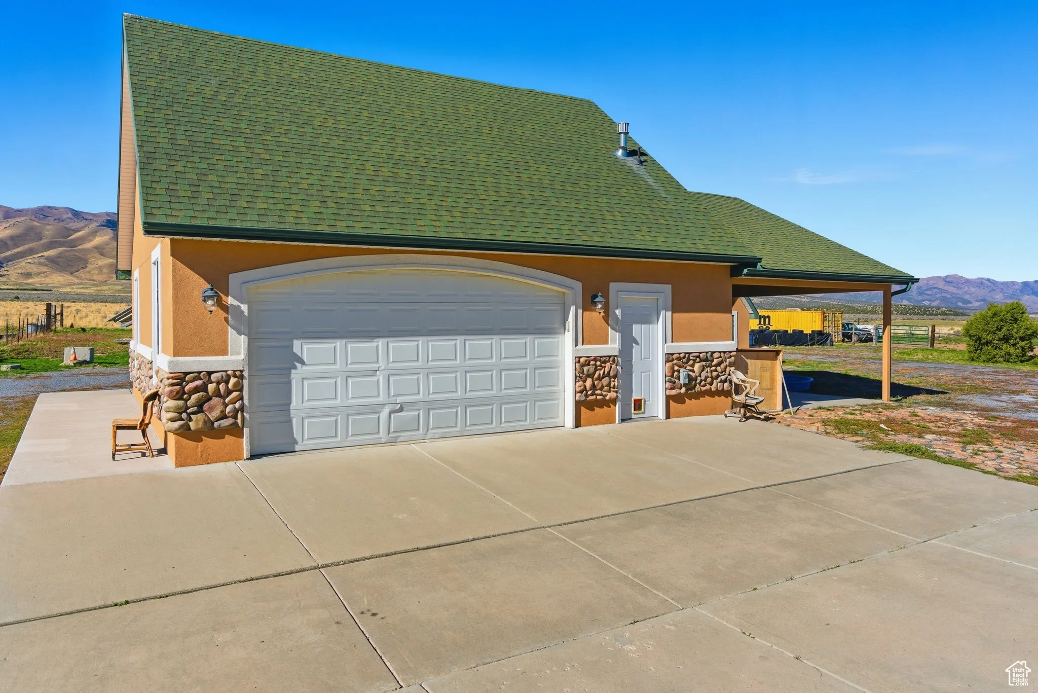 View of two car detached garage with a mountain view, stone siding and stucco siding.