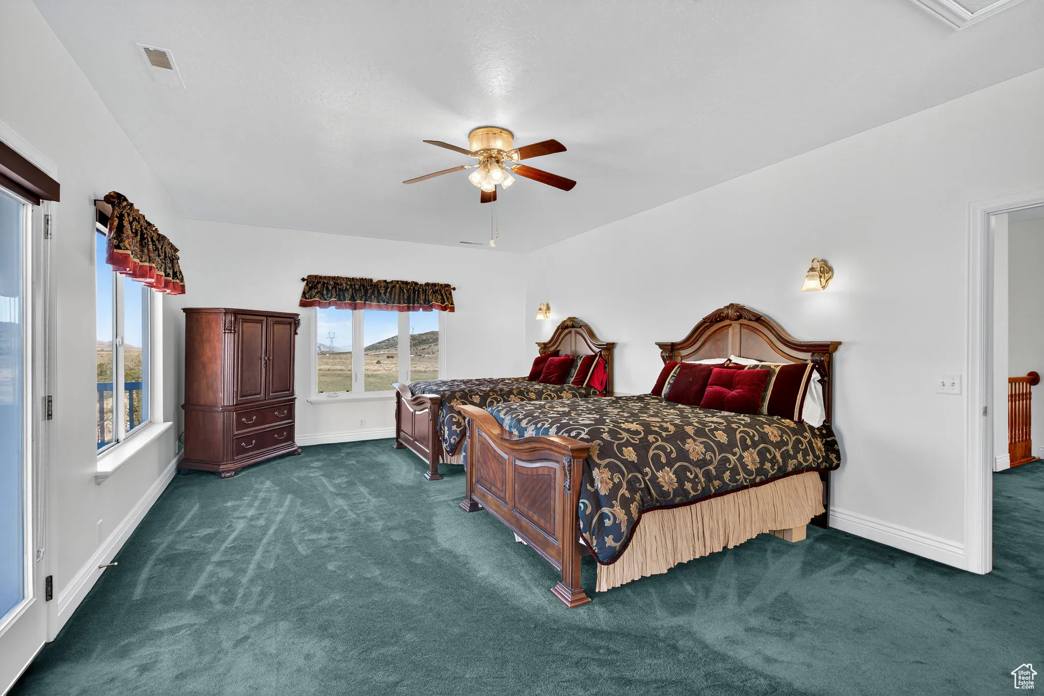 Bedroom with dark carpet and a ceiling fan.