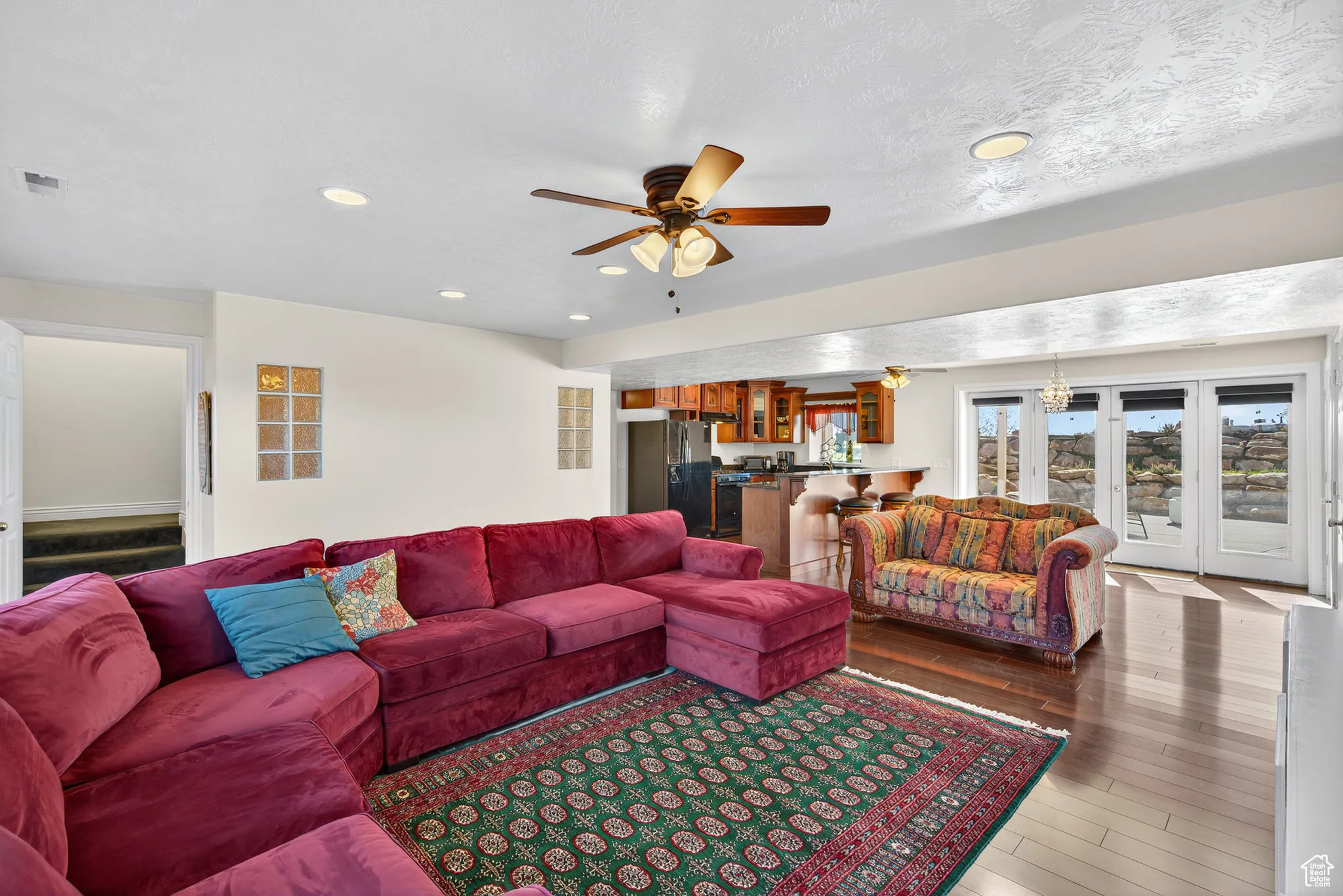 Basement living room featuring a ceiling fan, wood-style flooring, recessed lighting french walk out doors and a full kitchen.