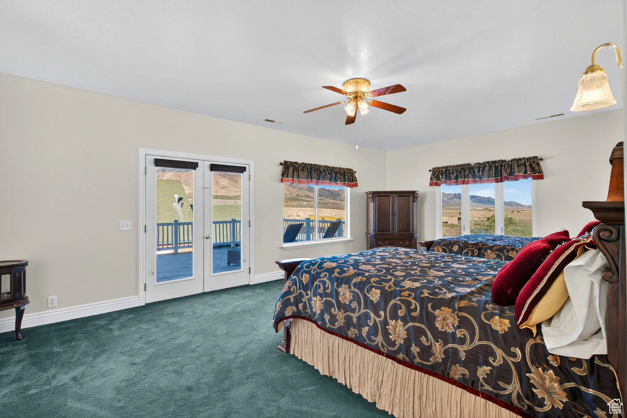 Large second floor bedroom with access to west balcony, carpet, french doors, and ceiling fan.