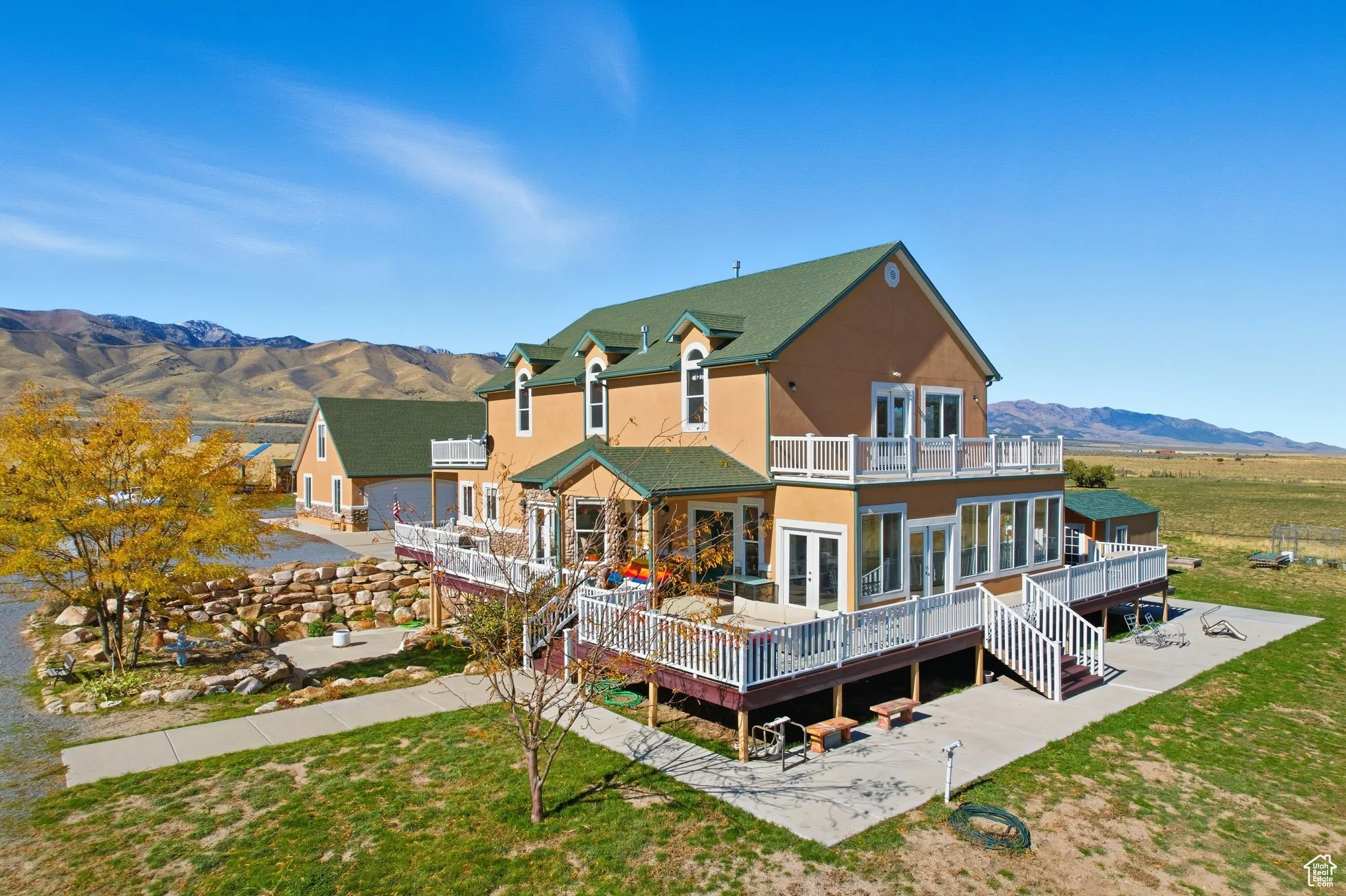 South west corner of home featuring french doors, stucco siding, a deck with mountain view, a yard, and stairs.