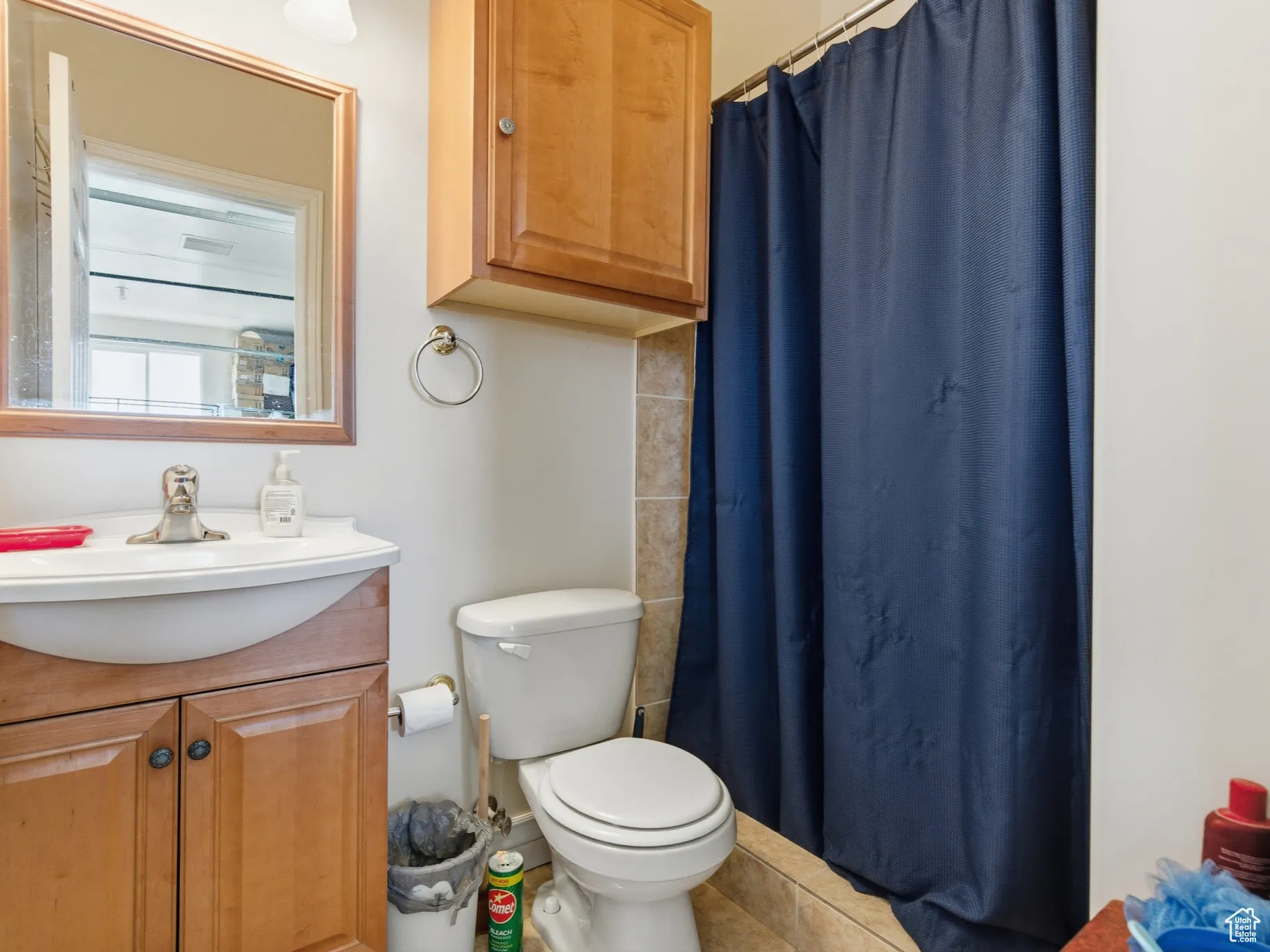 Garage bathroom featuring a shower with curtain, vanity.