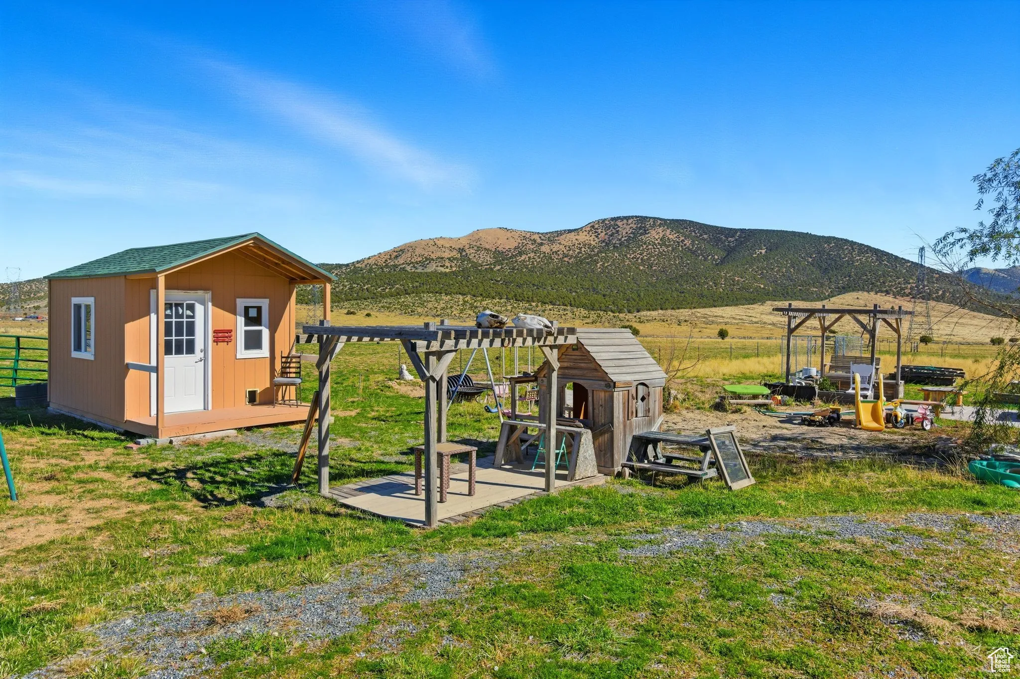View of playground with a pergola, a rural view, a out building, and a mountain view.