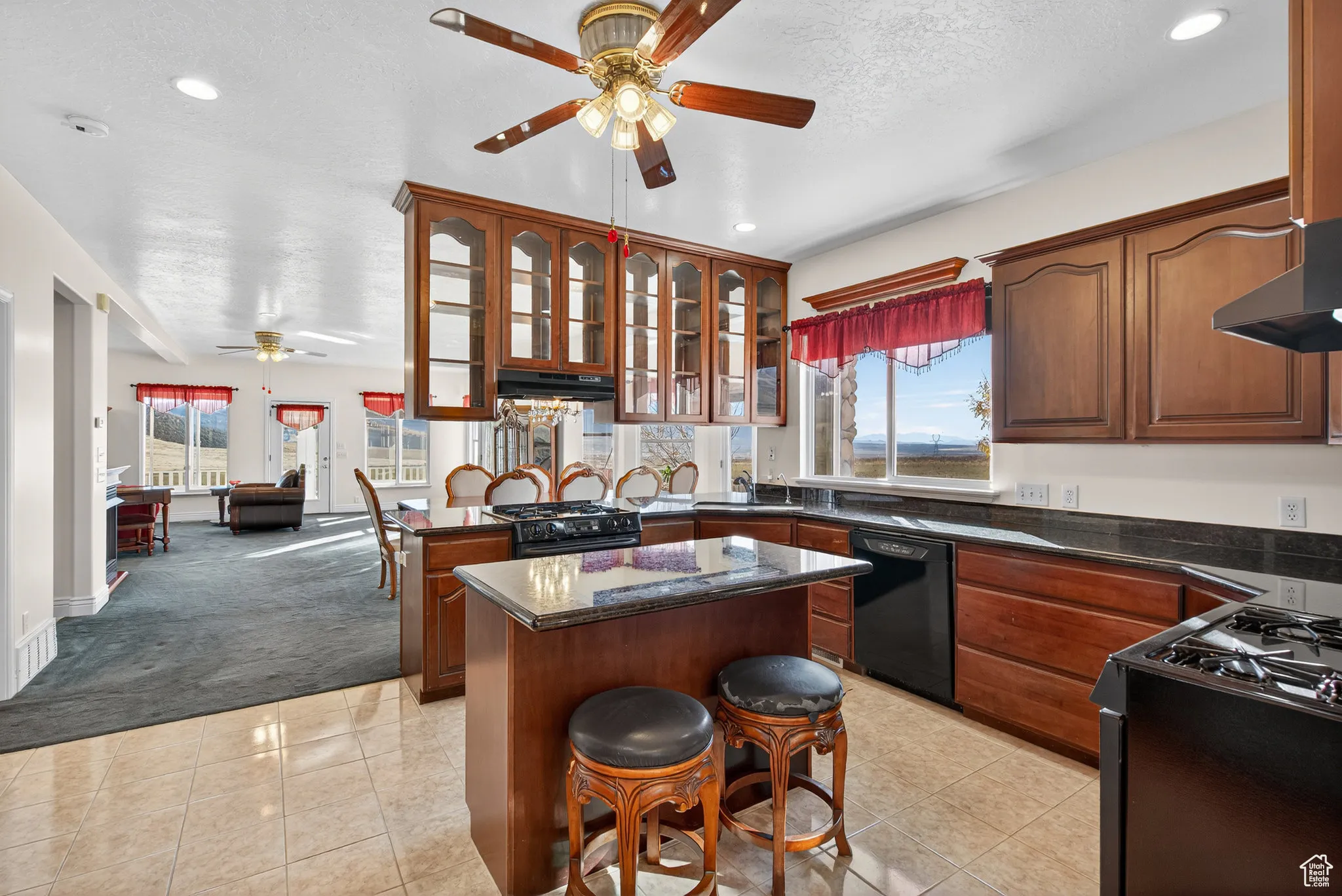 Kitchen with two gas ranges, ceiling fan, glass see through cabinets, a kitchen island.