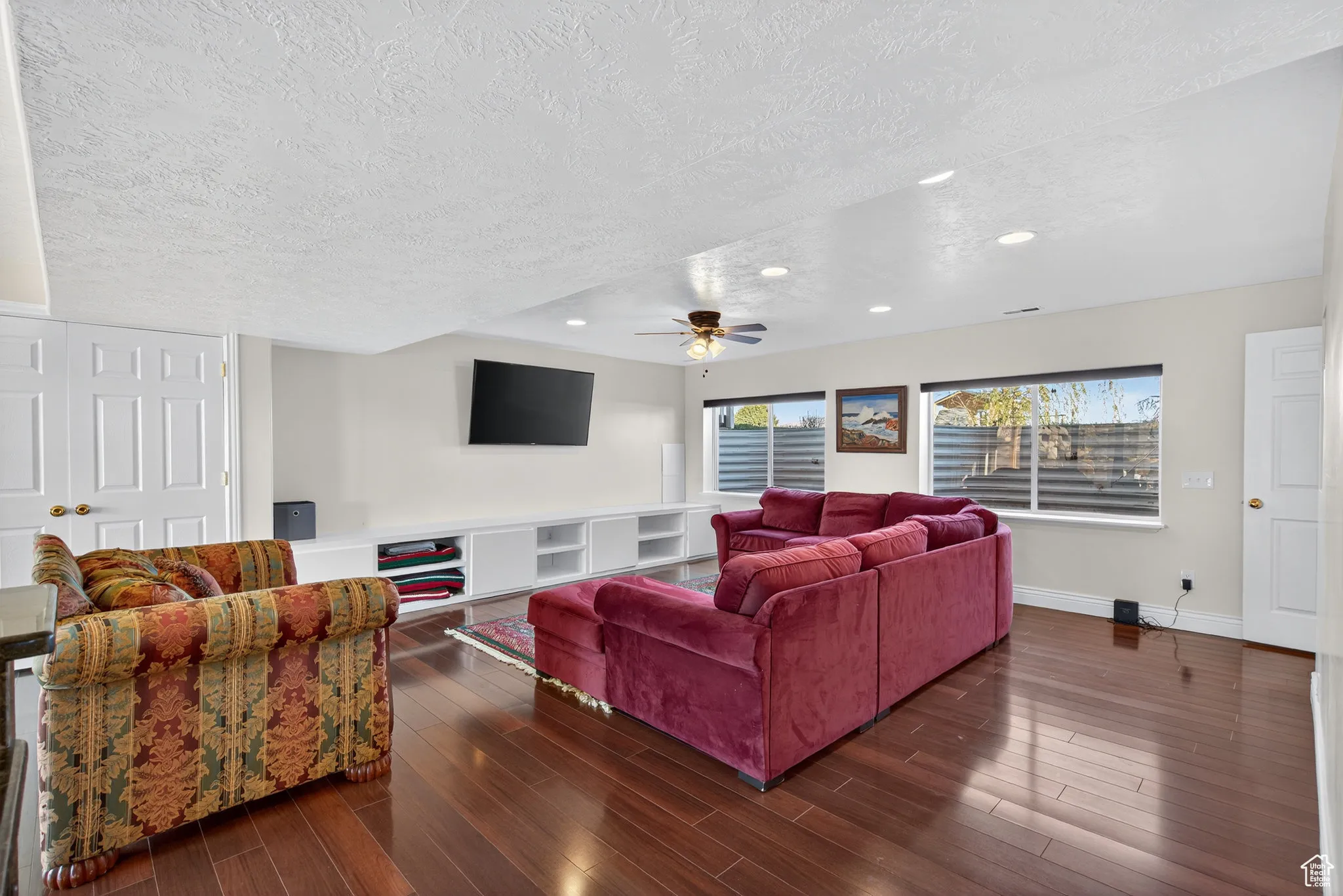 Basement living room with wood style floors, a ceiling fan, and recessed lighting.