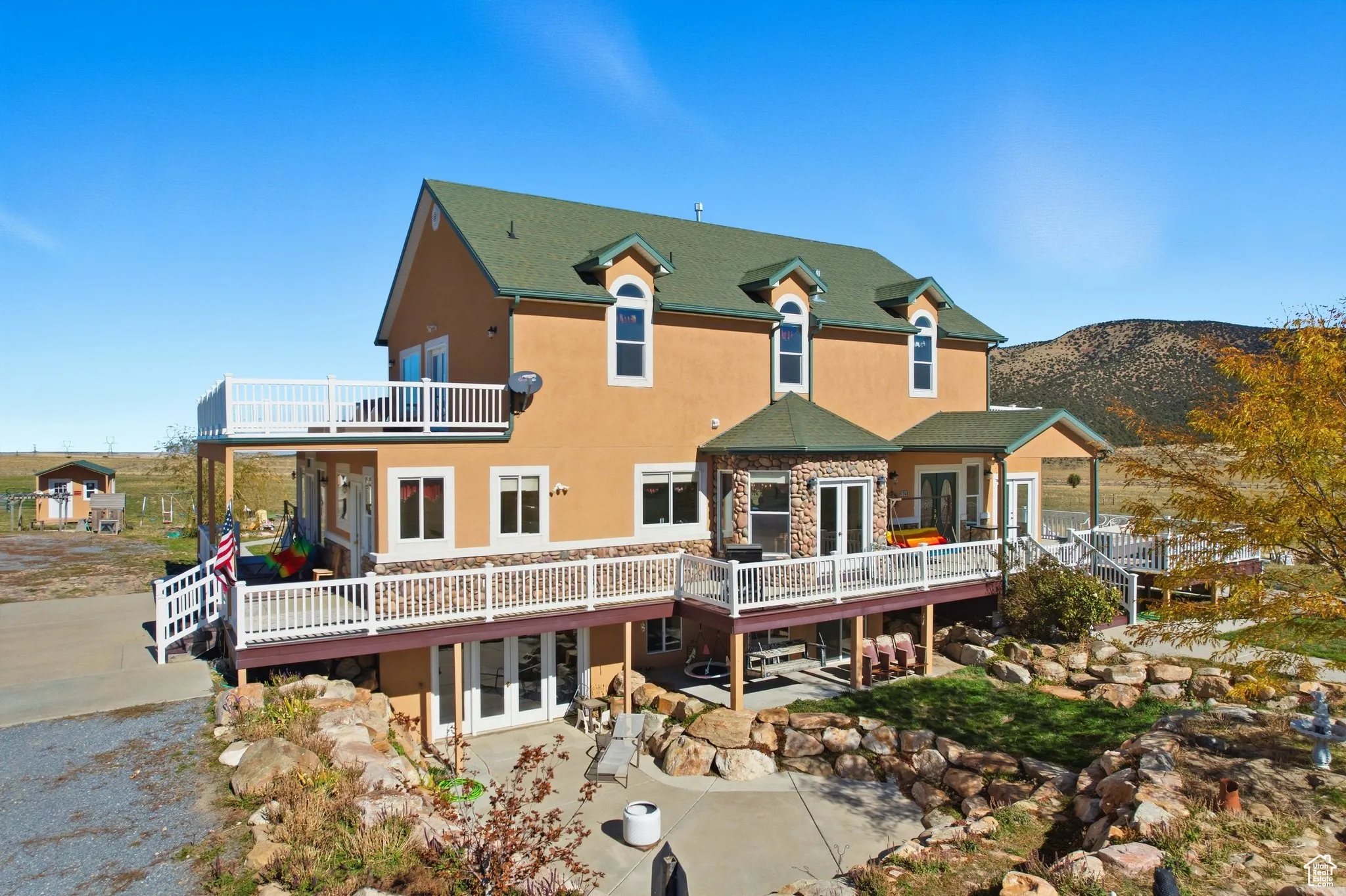 Elevated view of south side of home with french doors, stucco siding, a patio, and a deck.
