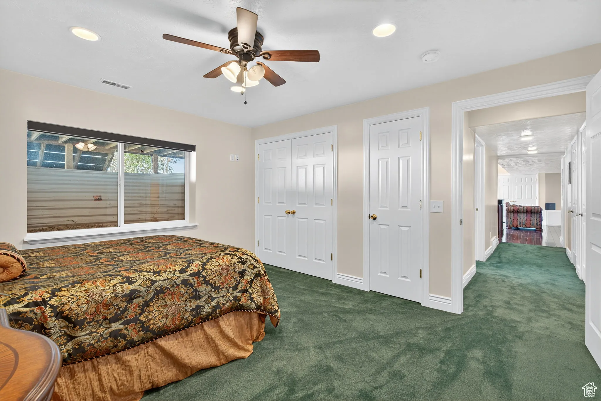 Basememnt bedroom with dark colored carpet, multiple closets, recessed lighting, and a ceiling fan.