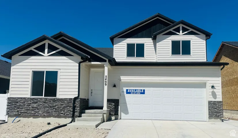 Craftsman house featuring stone siding, driveway, and a garage