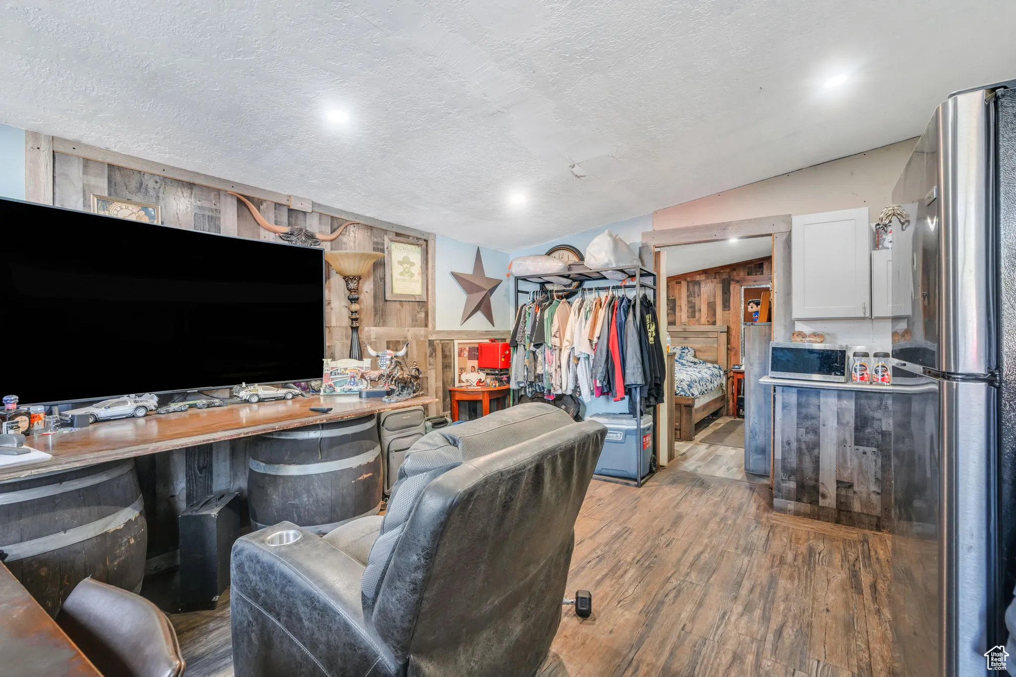 Living room with wood finished floors, a textured ceiling, lofted ceiling, and wood walls