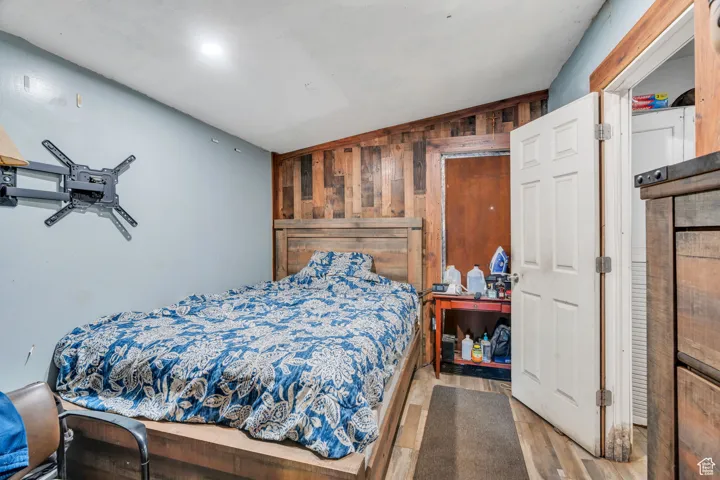 Bedroom with wooden walls, lofted ceiling, and wood finished floors