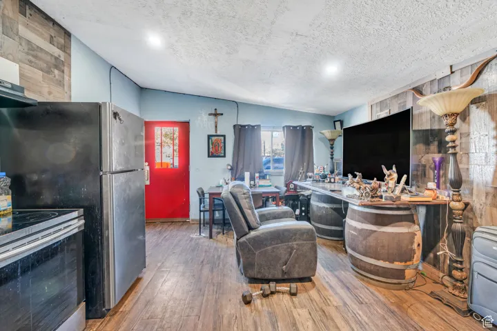 Kitchen with appliances with stainless steel finishes, wood finished floors, and a textured ceiling