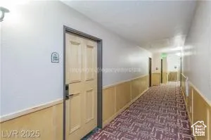 Hallway featuring a wainscoted wall and carpet flooring