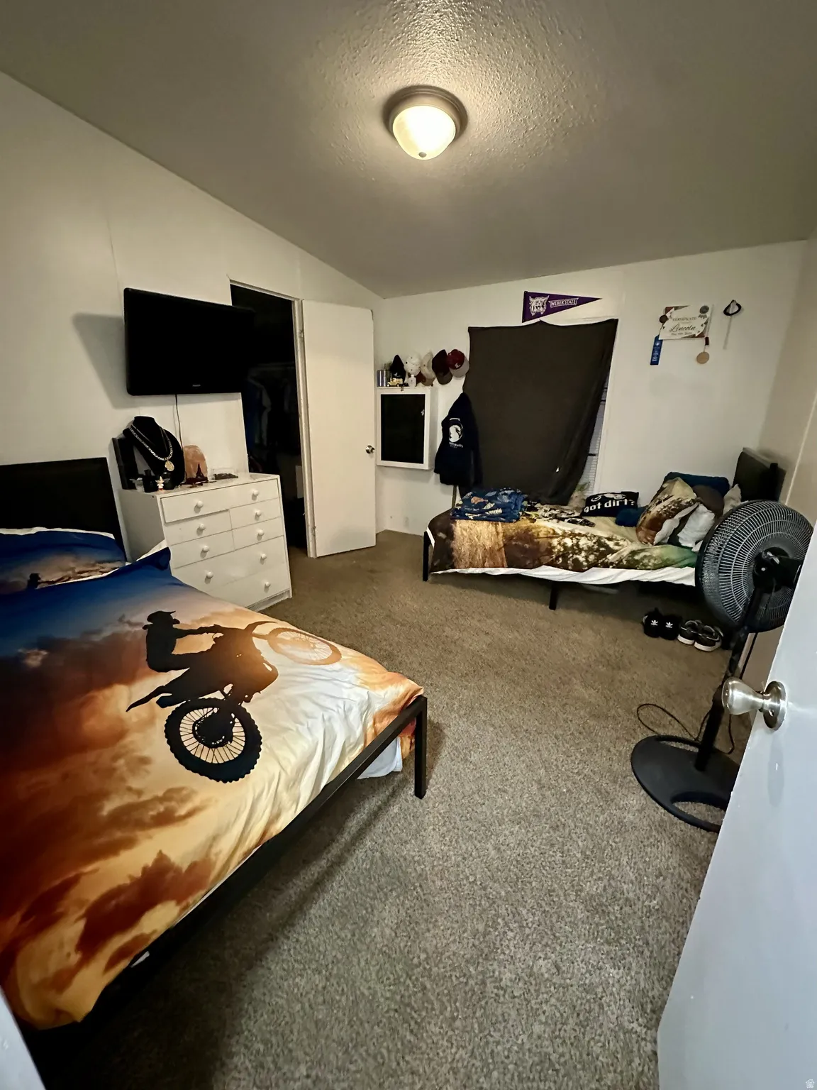Carpeted bedroom with a textured ceiling and a closet