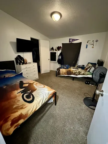 Carpeted bedroom with a textured ceiling and a closet